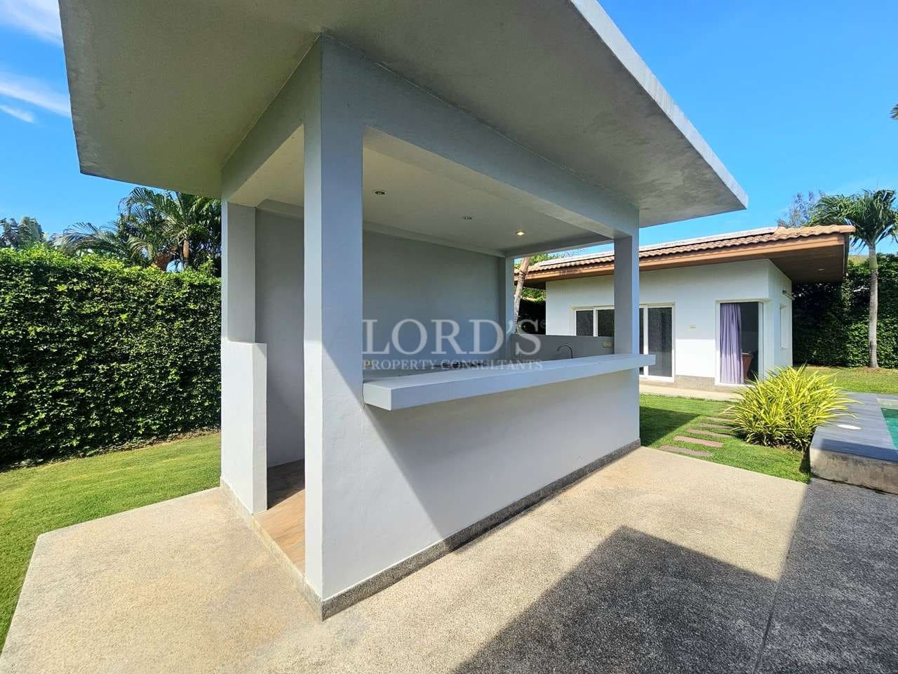 Covered outdoor bar counter beside the swimming pool in a modern luxury tropical villa.