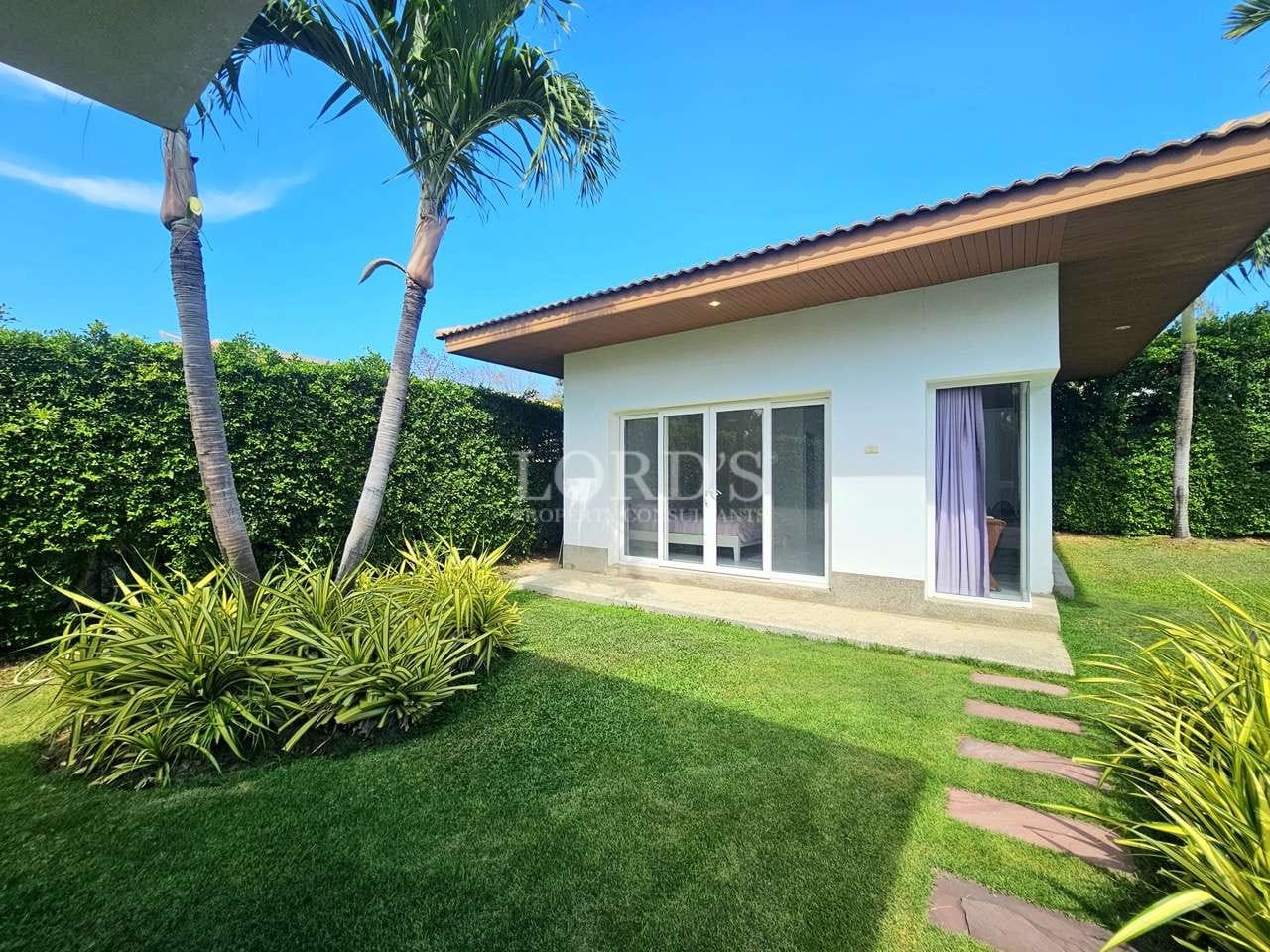 Modern garden-view villa exterior with sliding glass doors, private lawn, palm trees, and landscaped greenery.