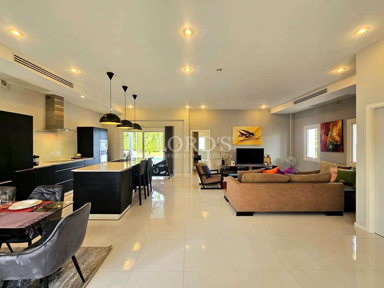 Spacious modern open-plan living room and kitchen with glossy tiled floor, black kitchen island, pendant lights, and comfortable seating area.
