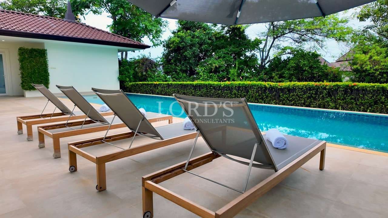 Luxury villa poolside sun loungers with umbrellas and private swimming pool.