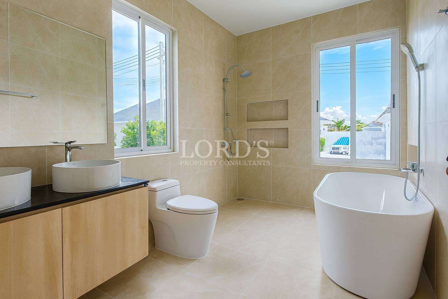 Modern bathroom with freestanding bathtub, walk-in shower, and double vanity in neutral beige tones
