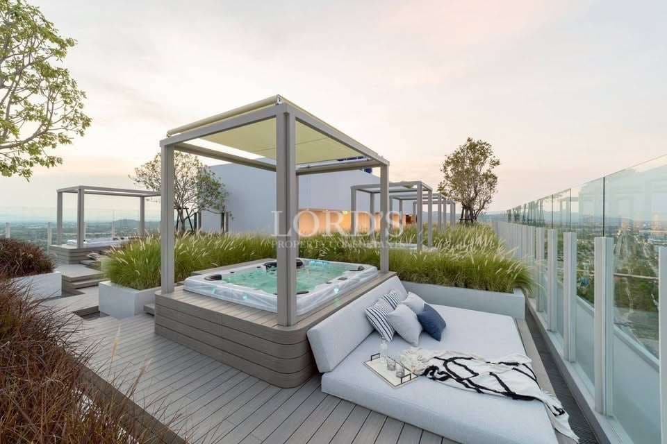 Luxury rooftop terrace with outdoor jacuzzi, pergola cabanas, modern lounge seating, and panoramic city skyline views.