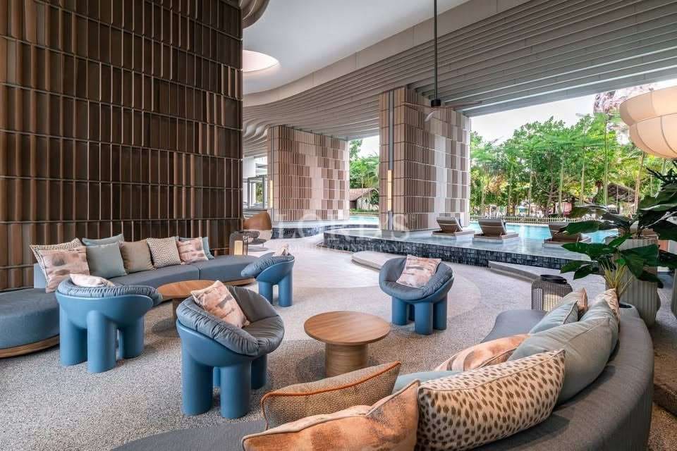Luxury open-air lounge with modern curved seating, textured architectural columns, and a tranquil poolside view surrounded by greenery.
