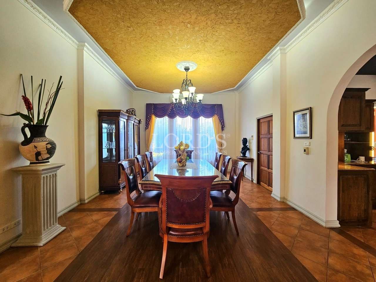 Elegant formal dining room with wooden dining table, classic chairs, and chandelier lighting.
