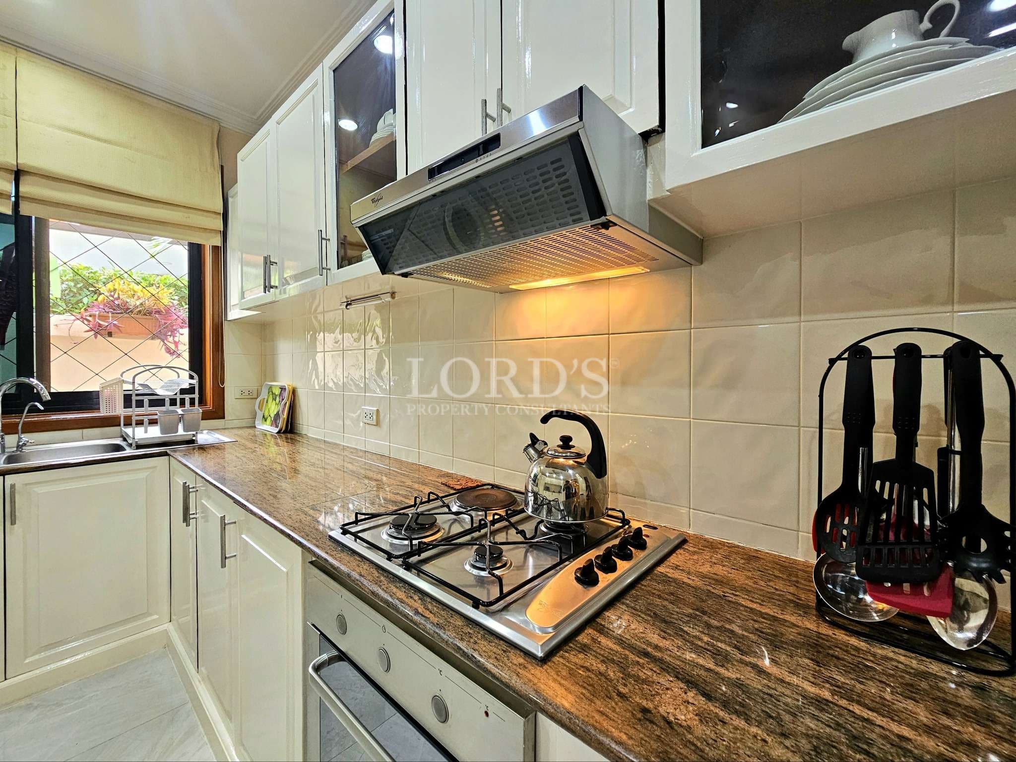 Modern kitchen with white cabinets, granite countertop, built-in gas stove, and stainless steel range hood