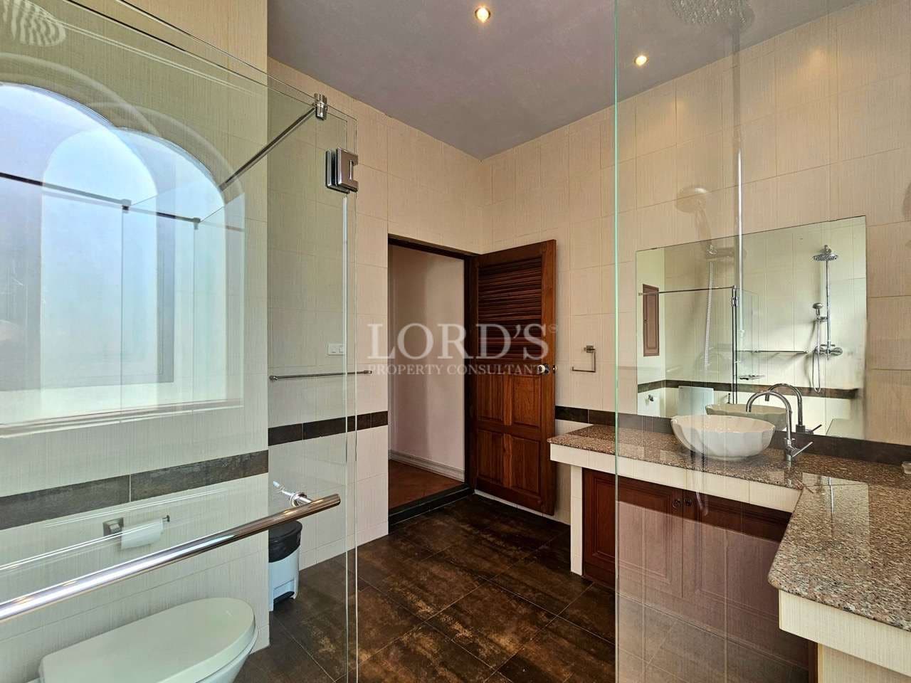 Spacious modern bathroom with glass shower enclosure, granite vanity countertop, wooden cabinetry, and large mirror.