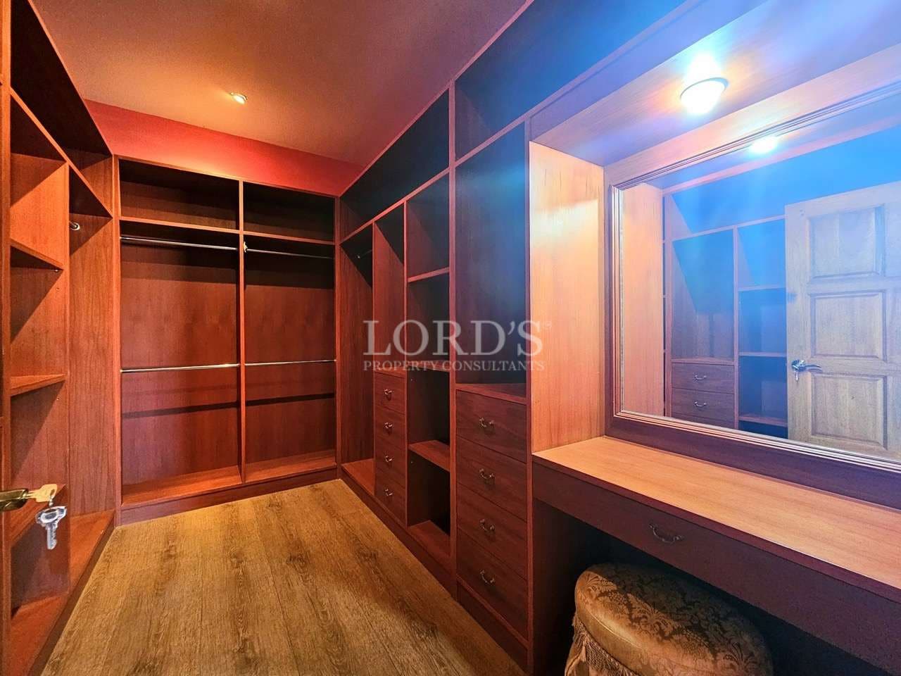Spacious wooden walk-in closet with mirror