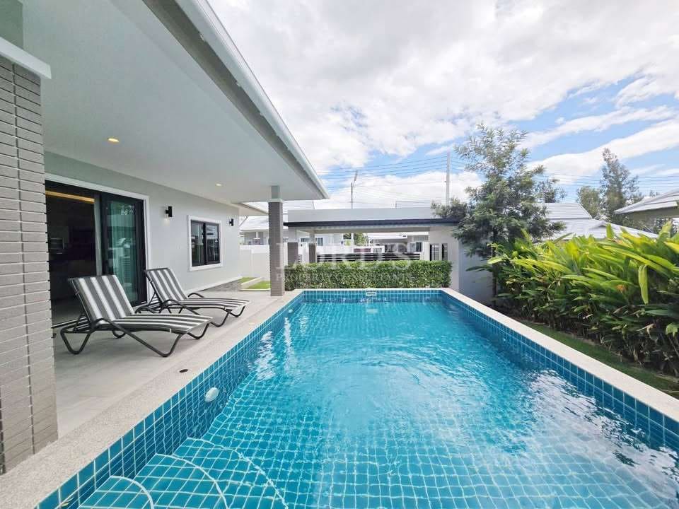 Private outdoor swimming pool with sun loungers beside a modern single-story villa.