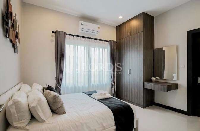Modern bedroom with double bed, built-in wardrobe, vanity desk, and soft natural light.
