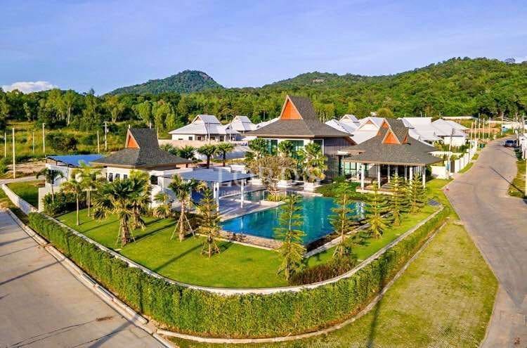 Aerial view of luxury villa community with private pools, landscaped gardens, and mountain backdrop.