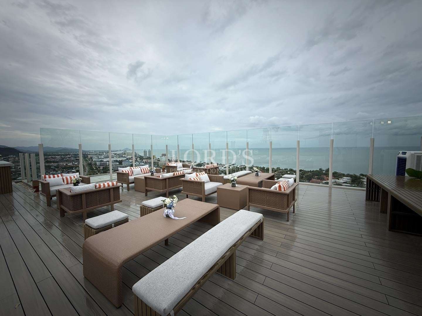 Luxury rooftop lounge with outdoor seating and panoramic sea and city views.