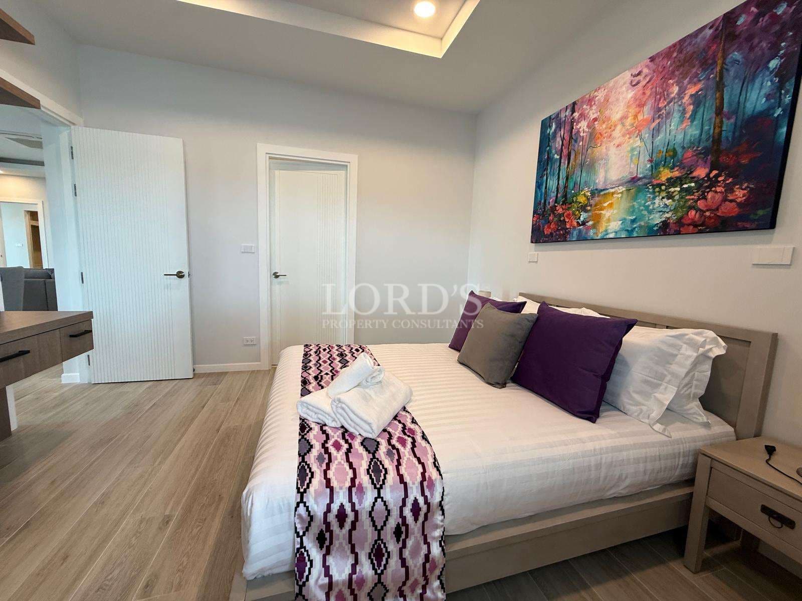 Modern luxury bedroom with double bed, decorative artwork, and minimalist interior design.
