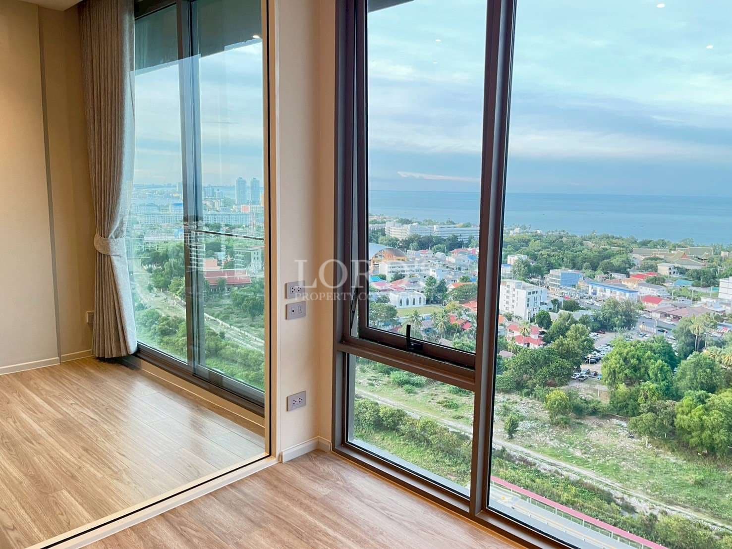 Floor-to-ceiling windows with panoramic city and sea view from a modern apartment.