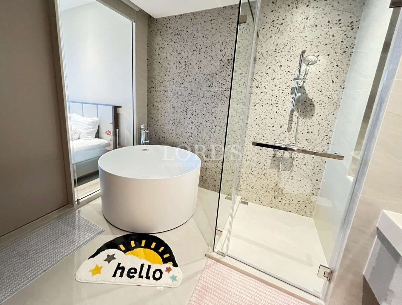 Modern bathroom with round freestanding bathtub, glass shower enclosure, and minimalist design.