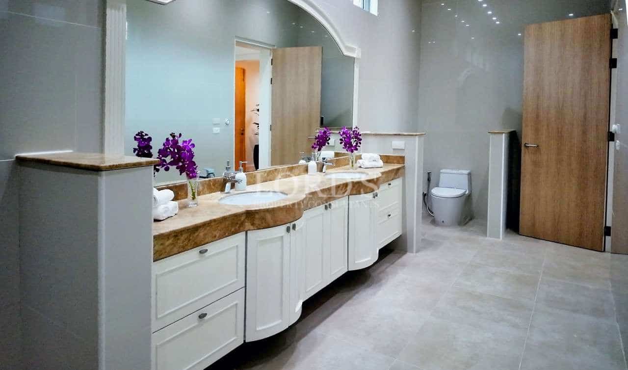 Luxury bathroom with double vanity, marble countertop, large mirror, and modern fixtures.