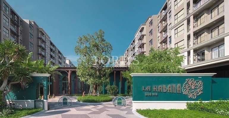 La Habana Hua Hin condominium entrance with tropical landscaping, modern low-rise apartment buildings, and elegant courtyard design.