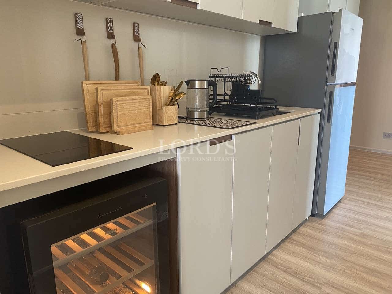 Modern kitchen with built-in appliances, wine cooler, induction cooktop, wooden cutting boards, and minimalist cabinetry.