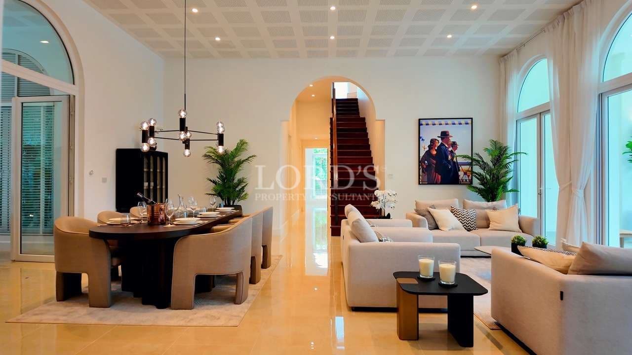 Luxury villa interior with open-plan living room, dining area, high ceiling, and staircase.