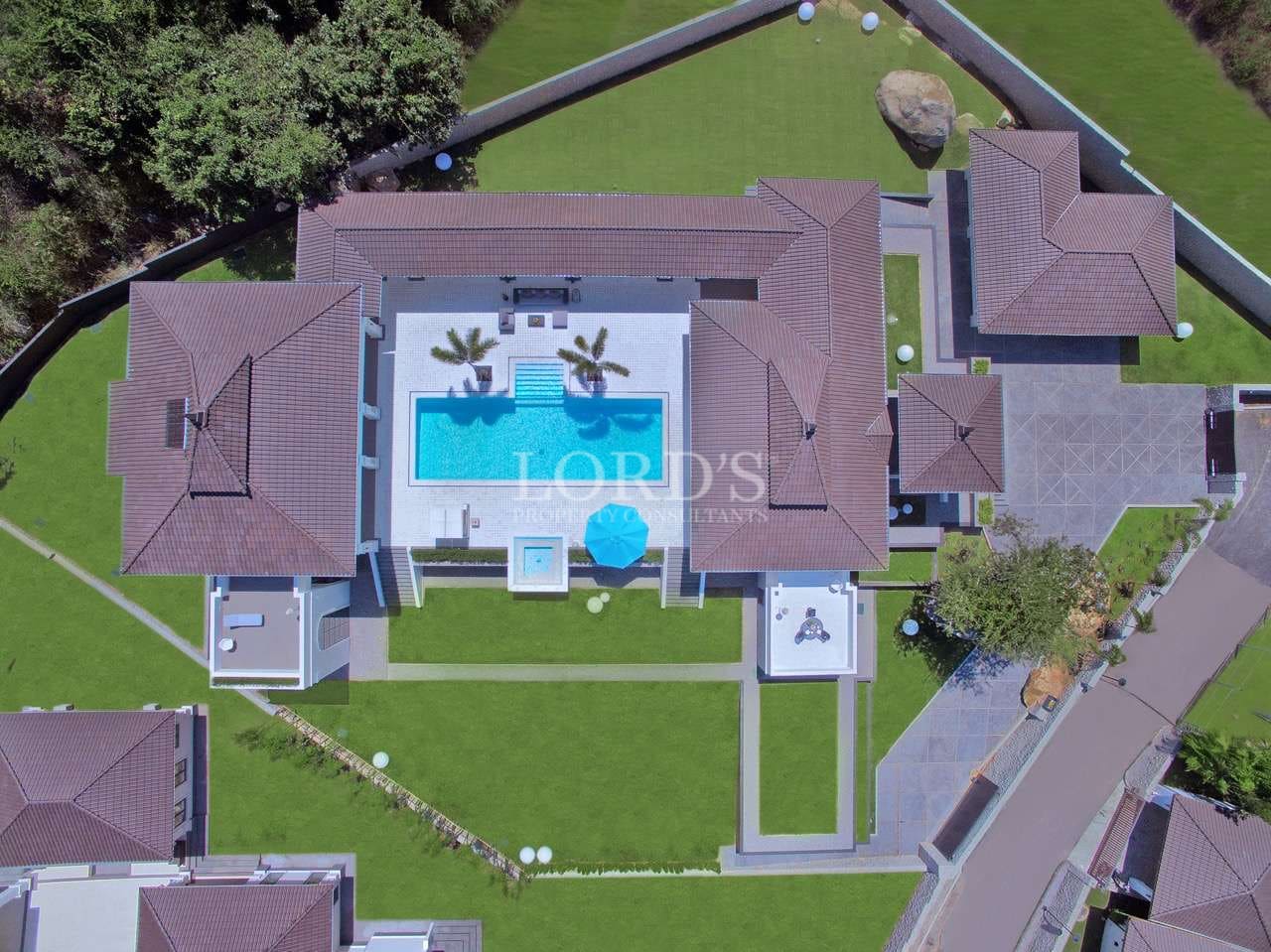 Top-down aerial view of a luxury villa complex with central swimming pool, symmetrical layout, and landscaped gardens.