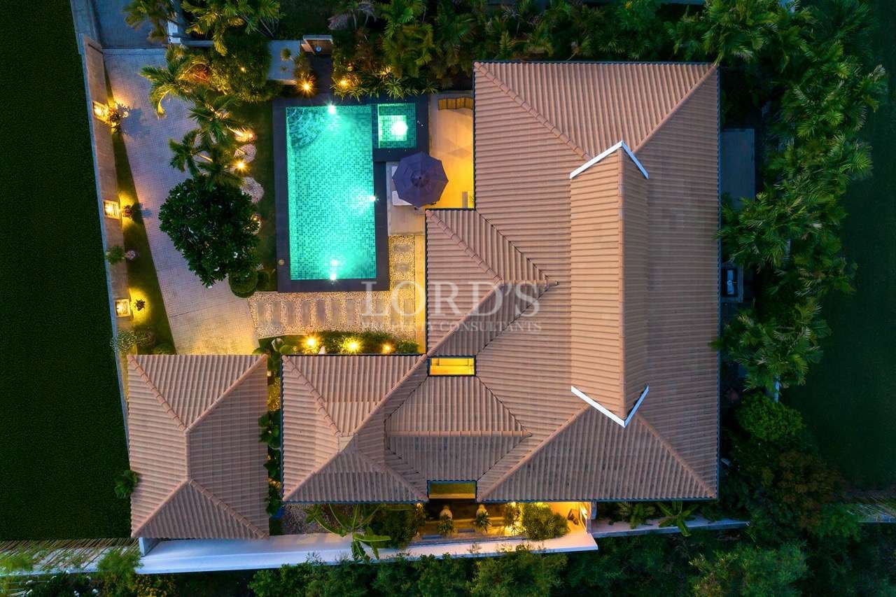 Top-down night aerial view of a luxury villa with illuminated swimming pool and landscaped garden.