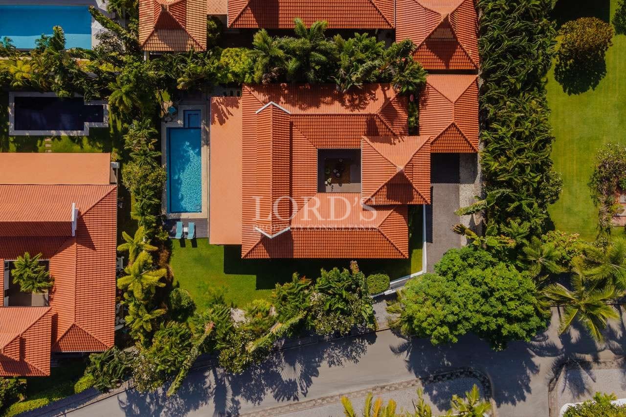 Top-down aerial view of a luxury villa with red-tiled roof, private swimming pool, and landscaped tropical garden.