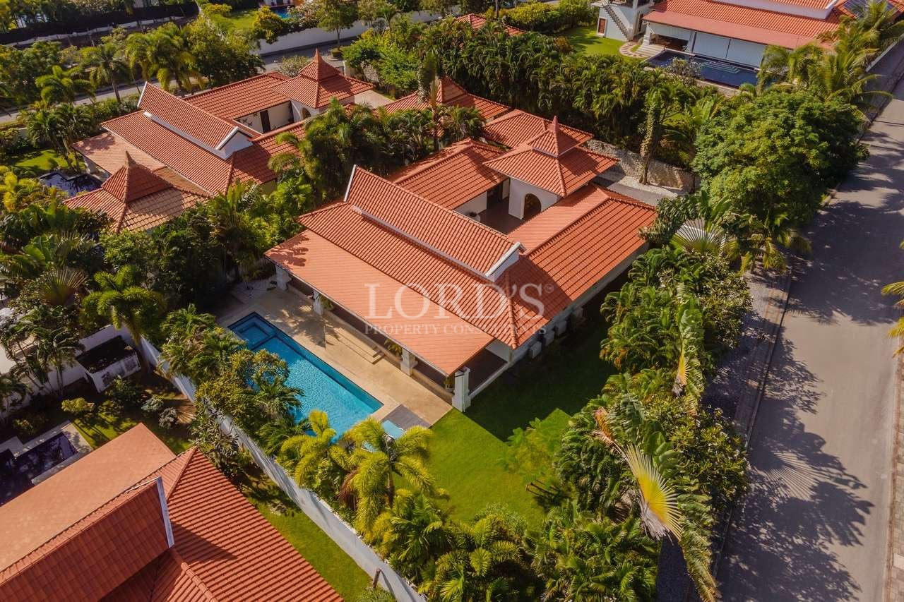 Aerial view of a luxury tropical villa with red-tiled roofs, private swimming pool, and landscaped garden.