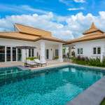 Luxury modern villa with private swimming pool, sun loungers, and landscaped tropical garden under blue sky.