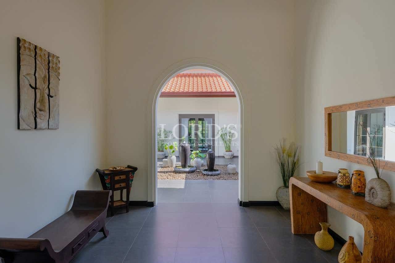 Elegant villa entrance hallway with arched doorway opening to a landscaped courtyard.