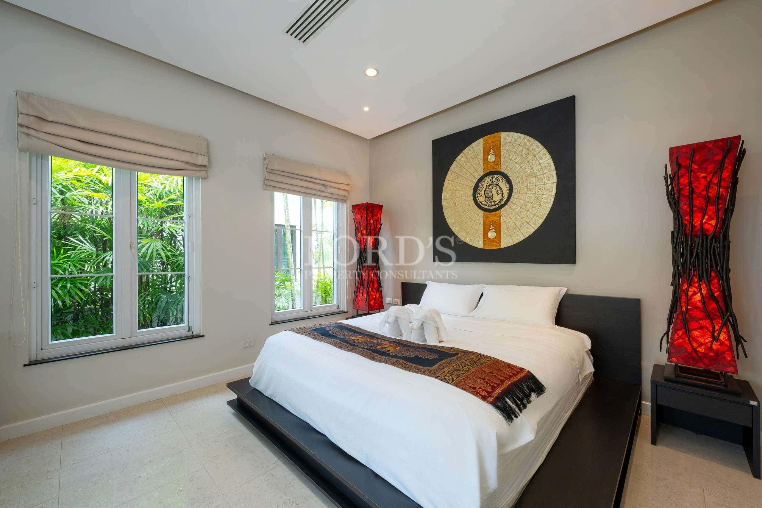 Elegant villa bedroom with king-size bed, Asian-inspired wall art, and garden-view windows.