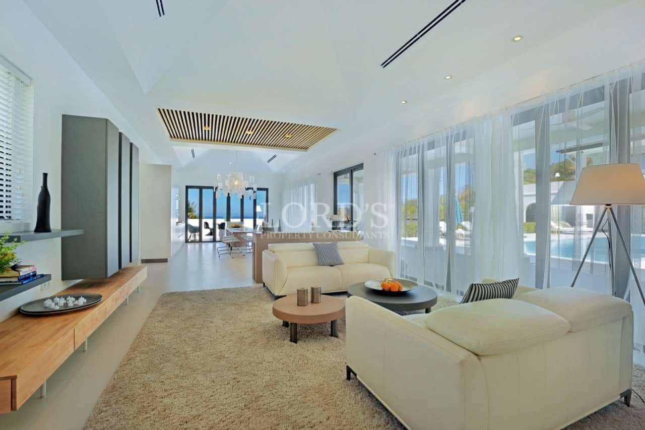 Spacious modern living room with white sofas, floor-to-ceiling windows, wooden ceiling detail, and open-plan luxury design.