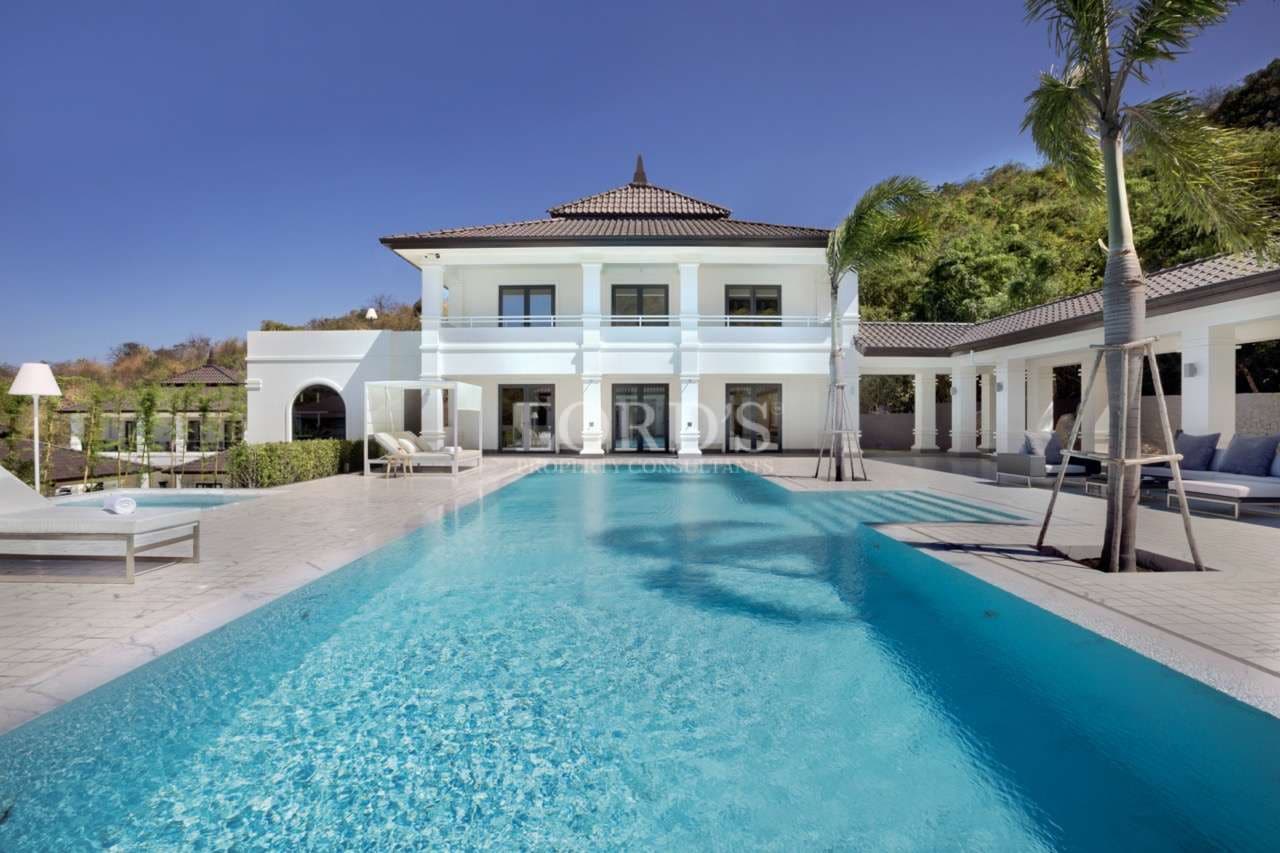 Luxury two-story villa with private swimming pool, palm trees, and modern white architecture.