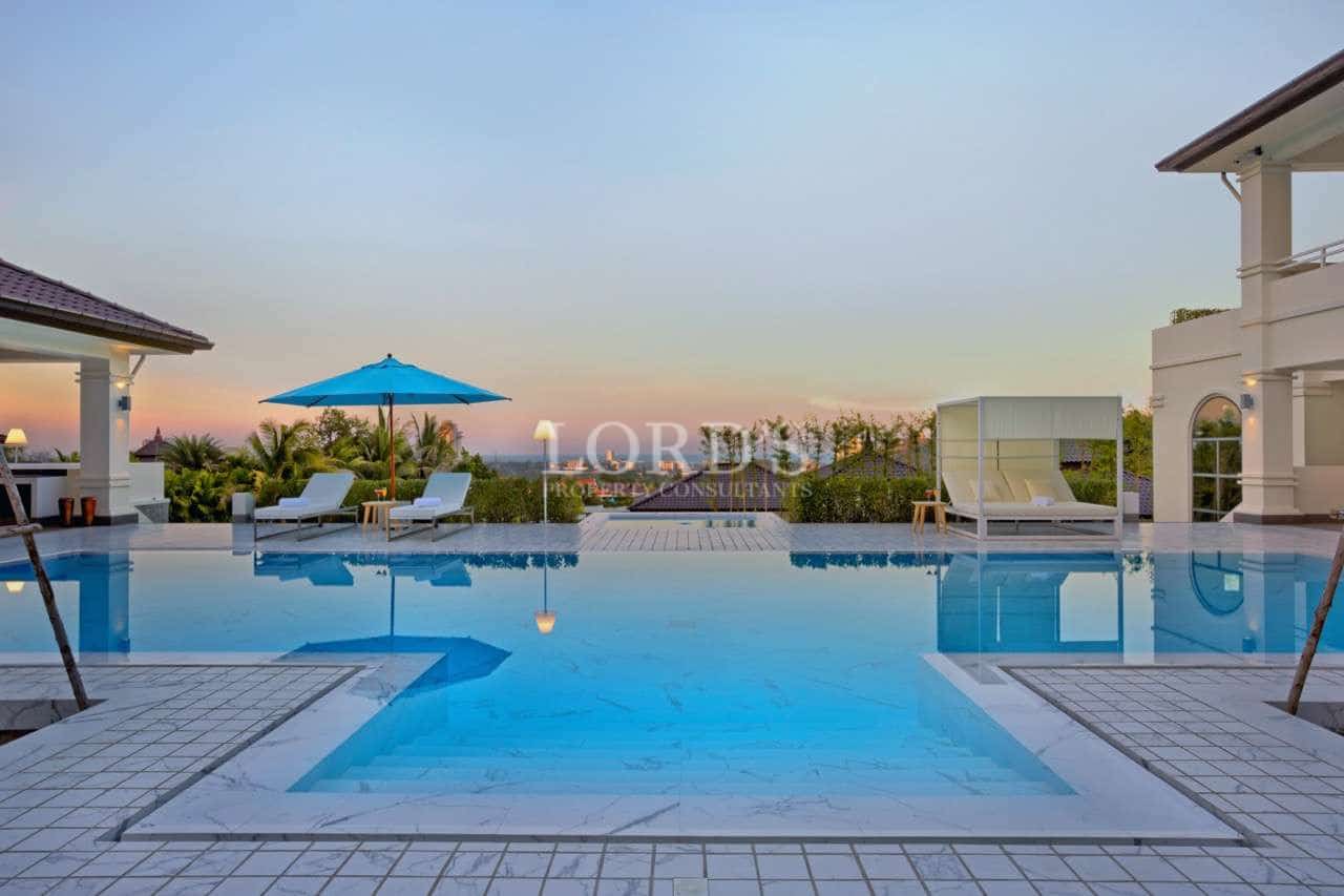 Luxury infinity swimming pool with sun loungers and panoramic sunset views.