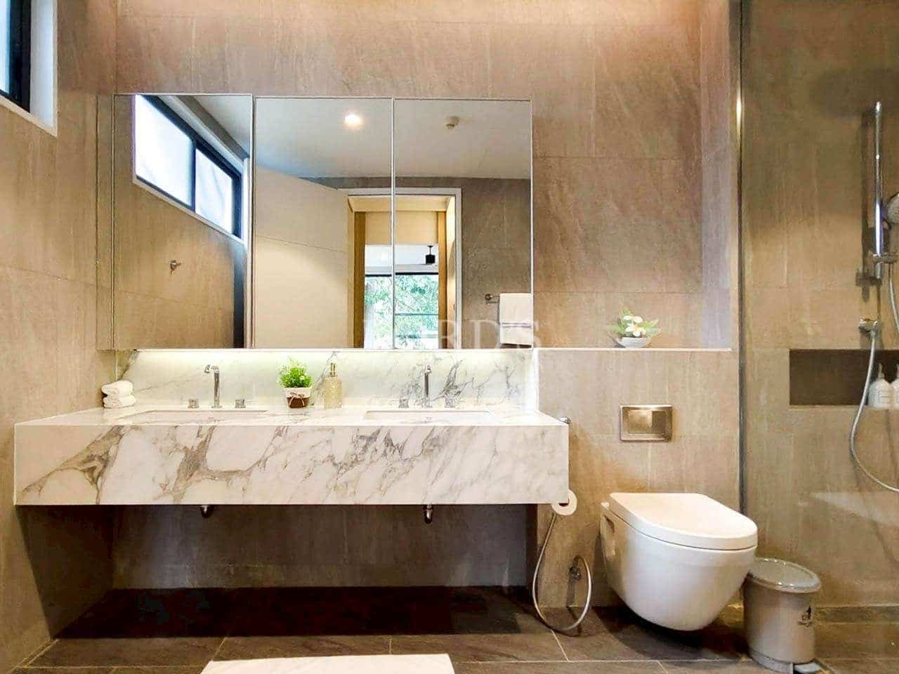 Modern bathroom with marble double vanity, wall-mounted toilet, and glass shower enclosure