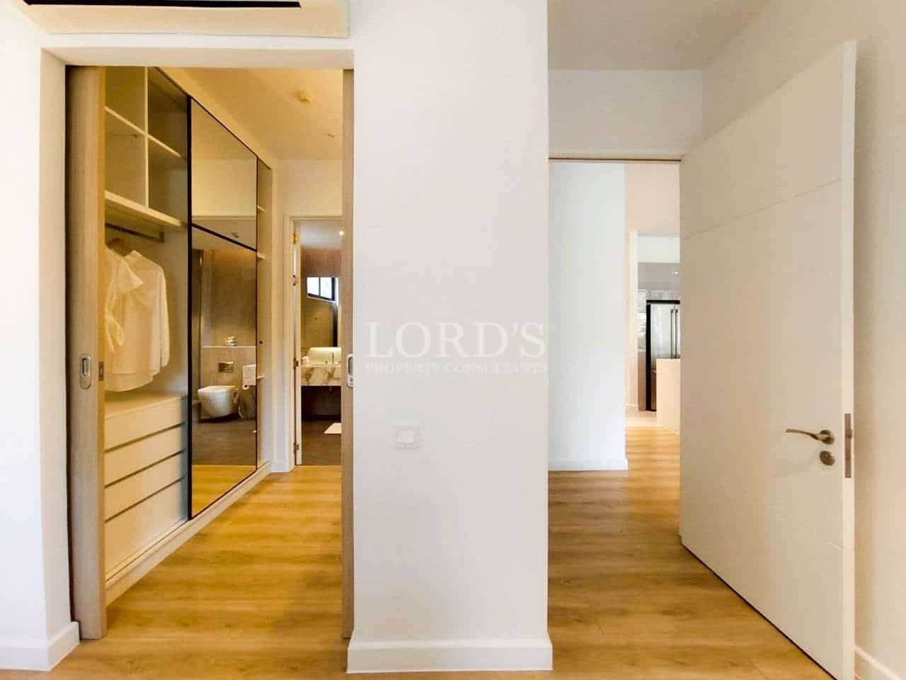 Modern hallway with built-in wardrobe, wooden flooring, and access to bathroom and bedroom