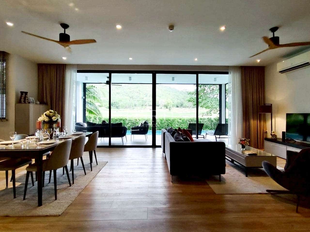 Spacious open-plan living and dining area with wooden floors, ceiling fans, and floor-to-ceiling glass doors