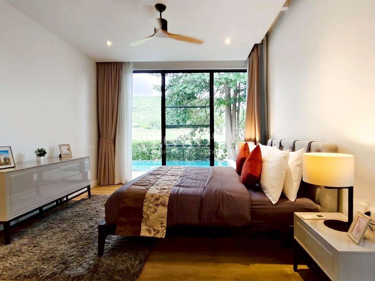 Spacious modern bedroom with king-size bed, ceiling fan, bedside lighting, and large glass doors