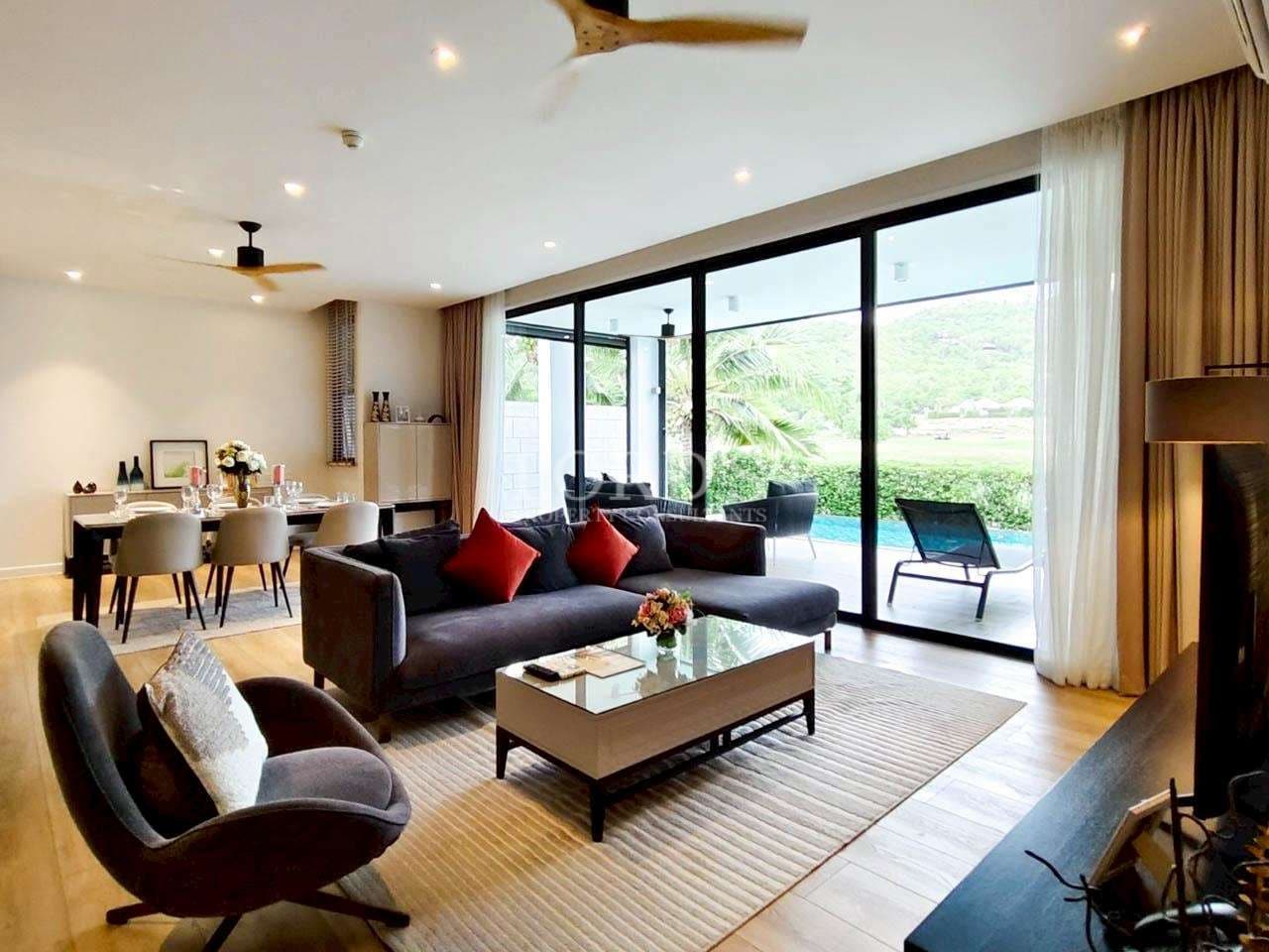 Open-plan living and dining room with modern furniture, wooden flooring, ceiling fans, and large glass doors