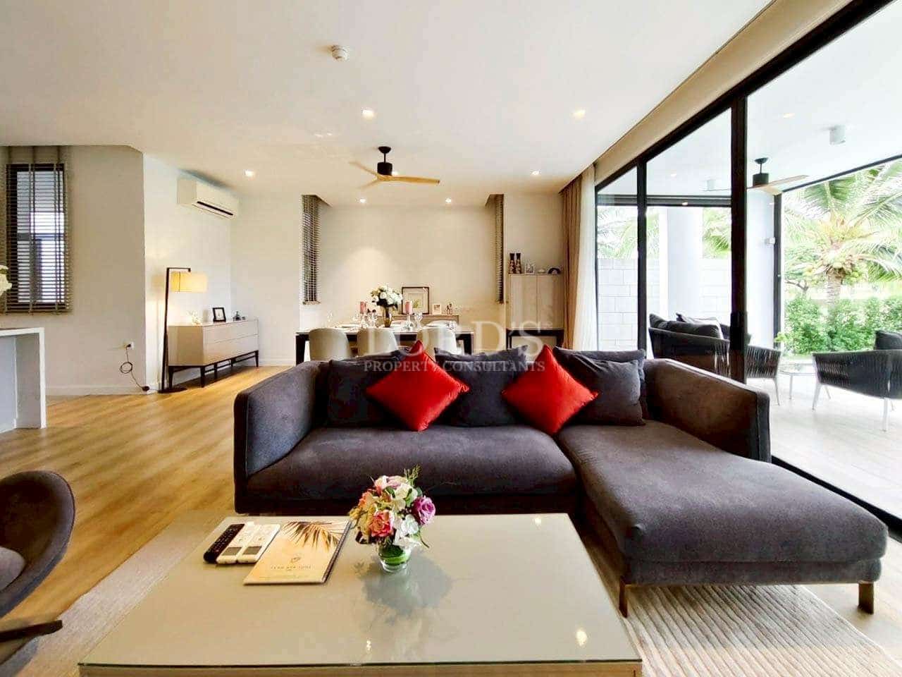 Open-plan living and dining area with sectional sofa, wooden flooring, and garden-facing glass doors