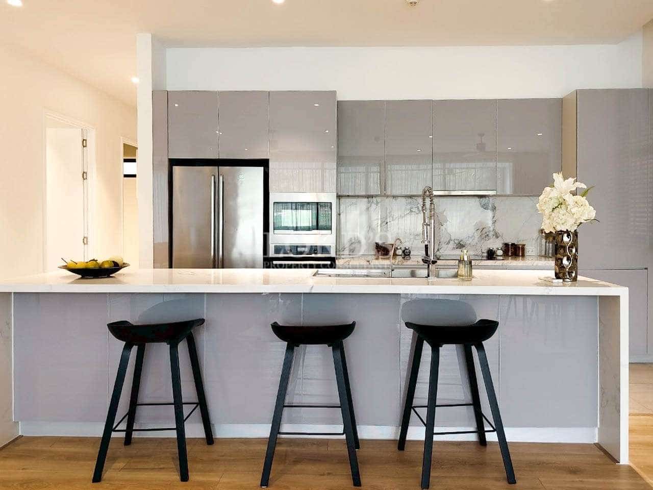 Modern kitchen with glossy gray cabinets, large island, bar stools, and built-in appliances