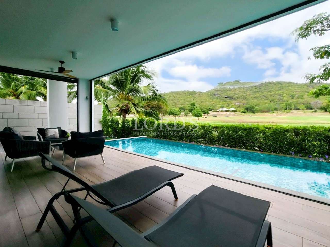 Private pool terrace with sun loungers, covered patio seating, and scenic mountain views