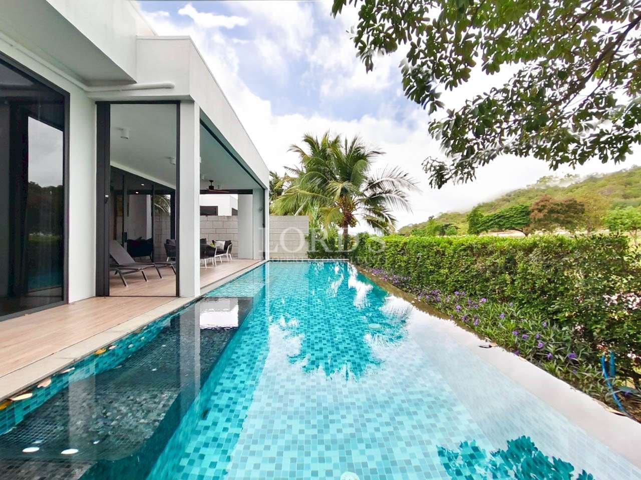 Modern villa with private swimming pool, glass walls, wooden deck, and landscaped garden