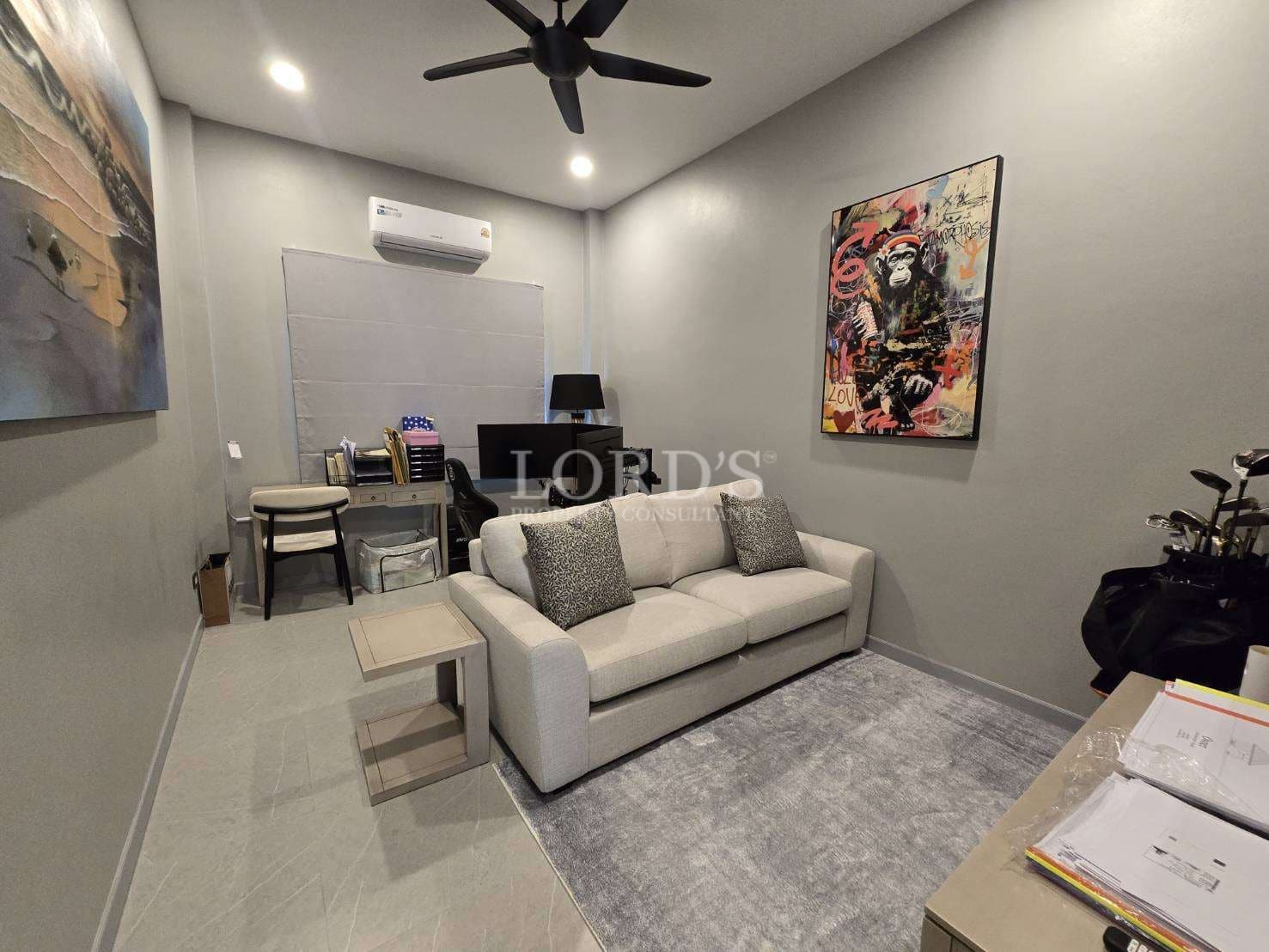 Modern home office and lounge room with sofa, work desk, wall art, and ceiling fan.