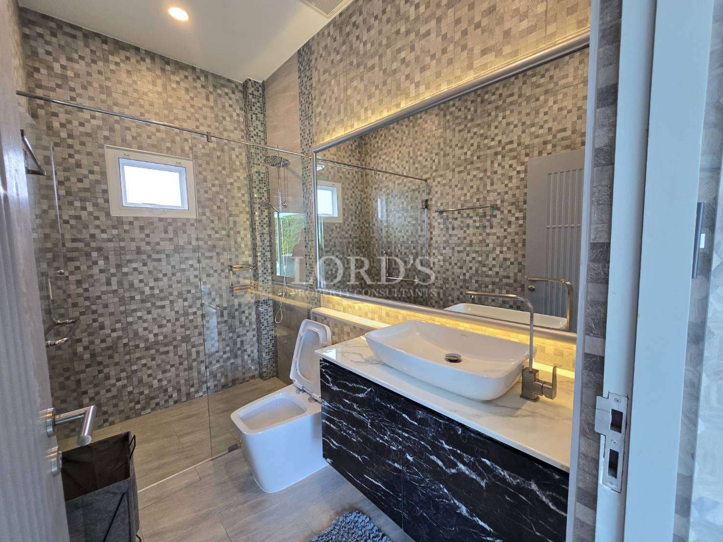 Modern bathroom with glass-enclosed shower, mosaic tile walls, floating vanity, and backlit mirror.