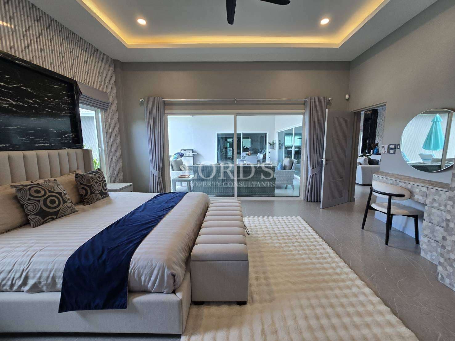 Luxury master bedroom with upholstered bed, LED ceiling lighting, sliding glass doors, and dressing area.