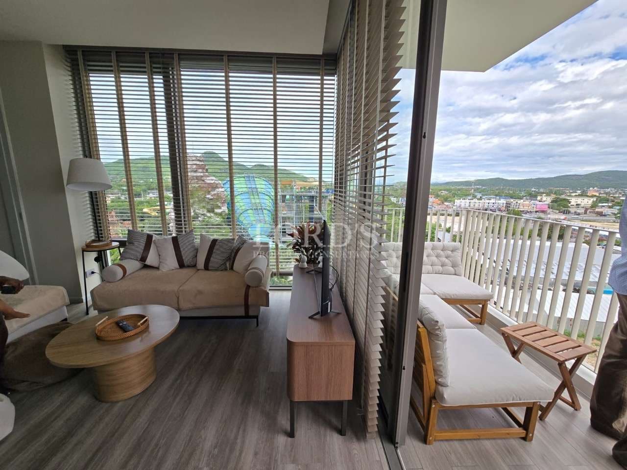 Modern living room with floor-to-ceiling windows, balcony seating, city view, and contemporary furniture.