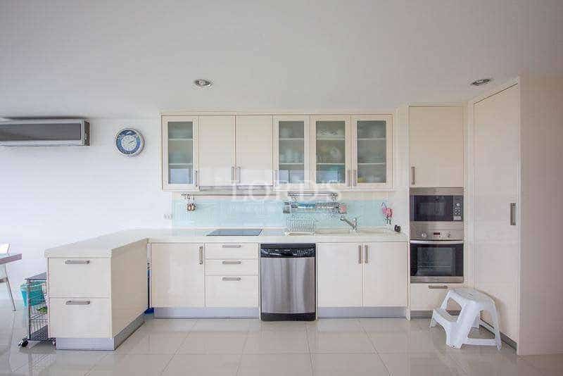 Modern white kitchen with built-in oven, dishwasher, overhead cabinets, and minimalist design