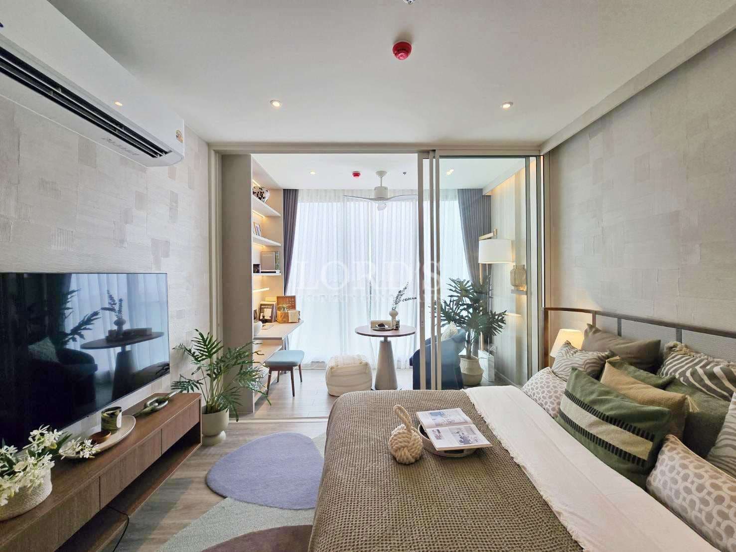 Modern bedroom interior with sliding glass partition, cozy bed, wall-mounted TV, indoor plants, study nook, and soft natural light from floor-to-ceiling curtains.
