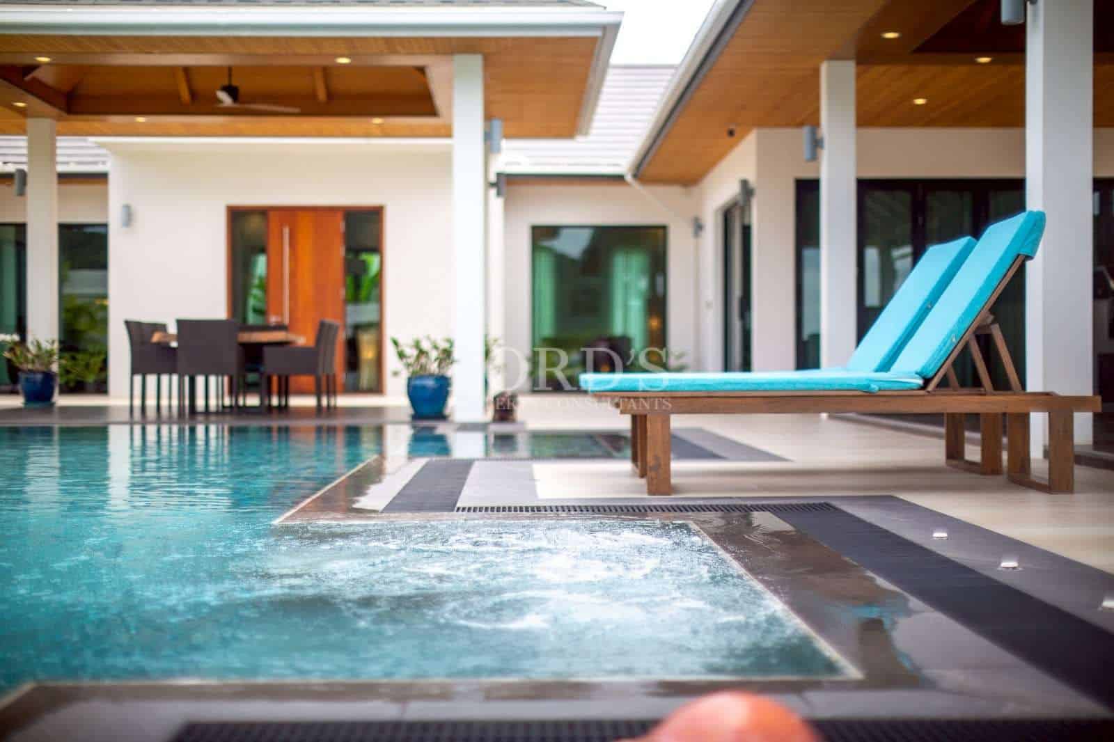 Luxury swimming pool with sun loungers and jacuzzi in a modern private villa.