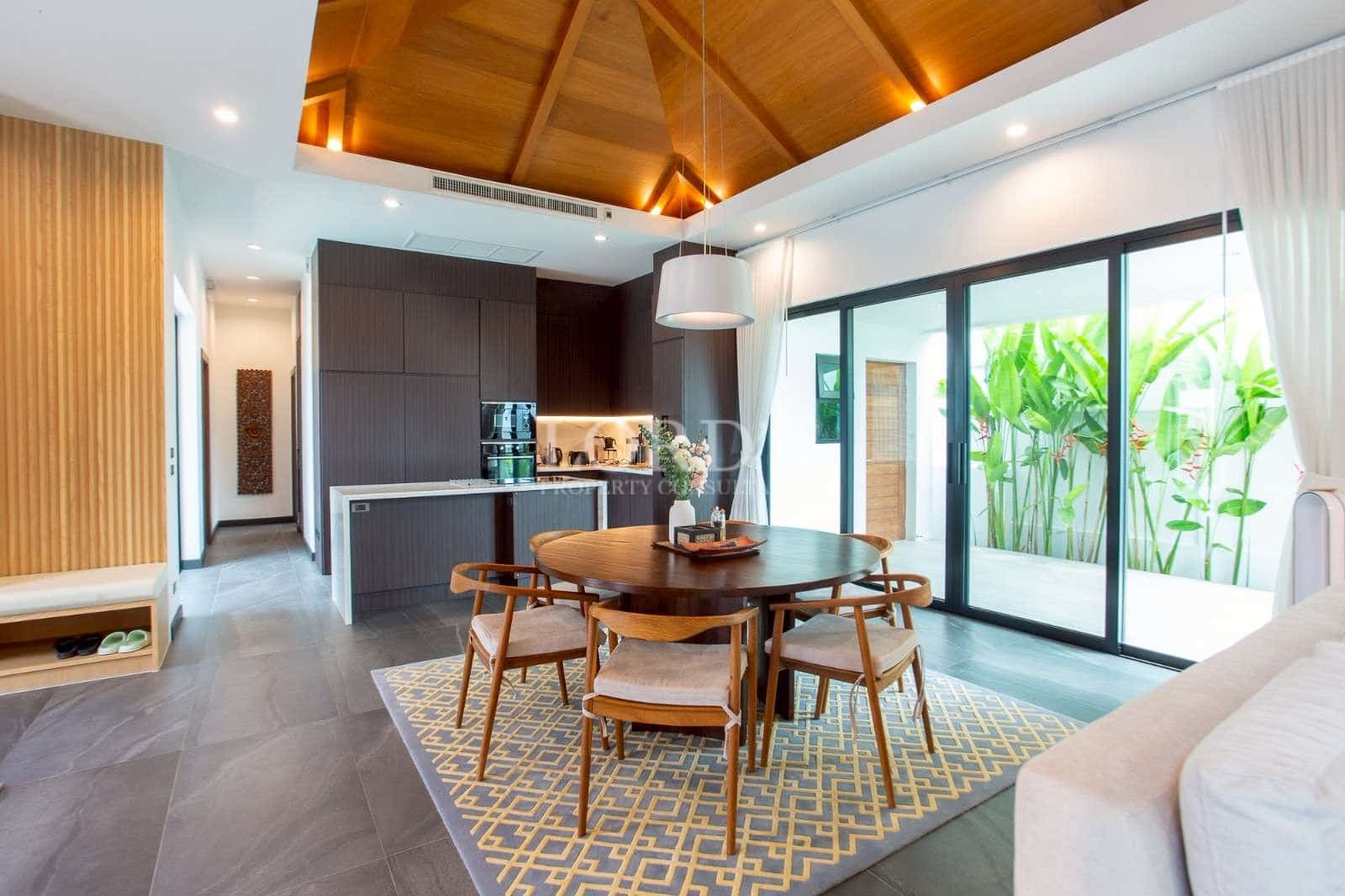 Open-plan dining and kitchen area with vaulted wood ceiling and sliding glass doors.