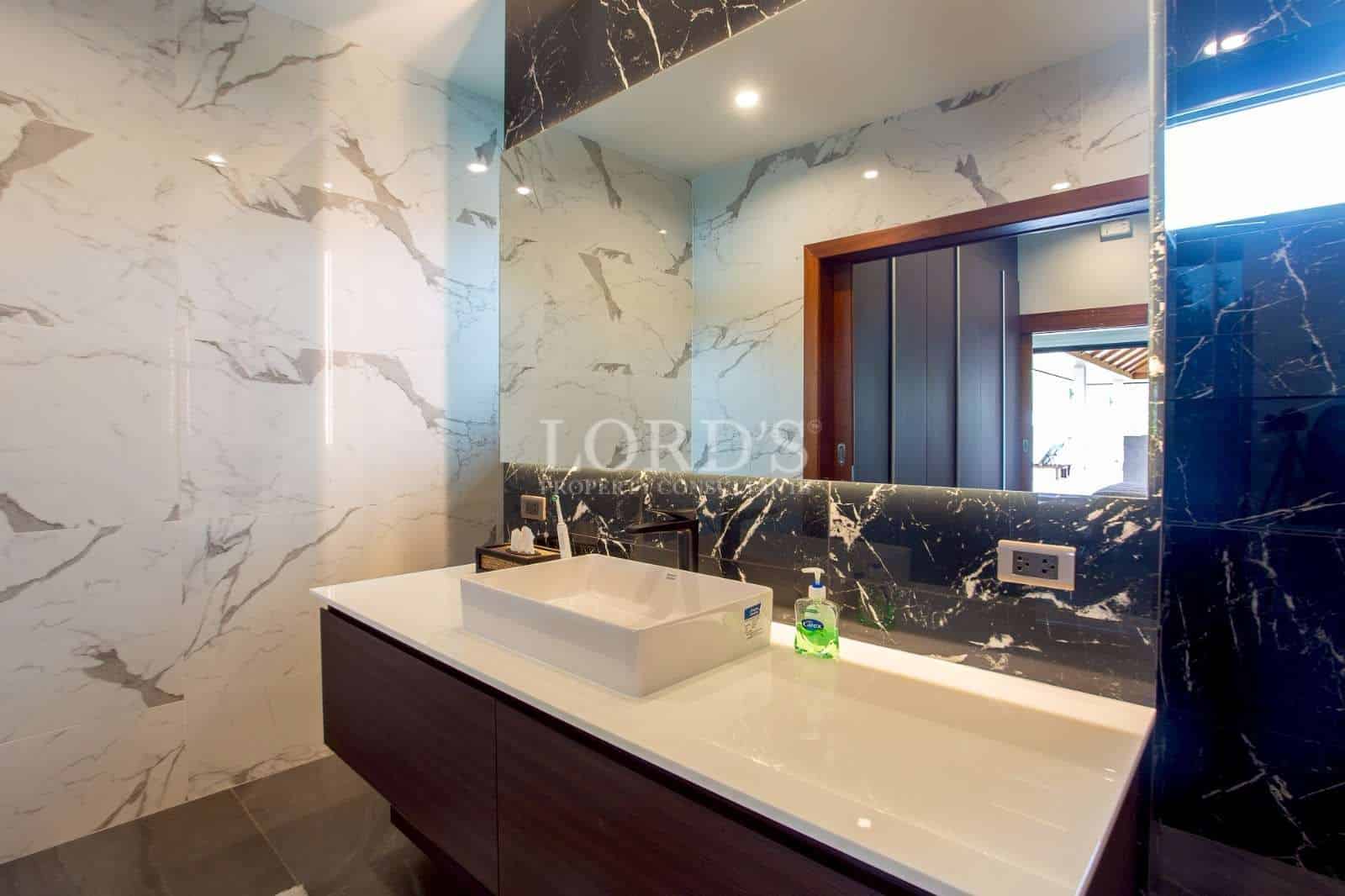 Modern bathroom vanity with marble wall tiles and rectangular vessel sink.